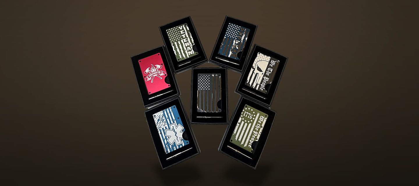 Seven anodised aluminium card-holder wallets in black gift boxes arranged in a ring, each engraved with a different design.