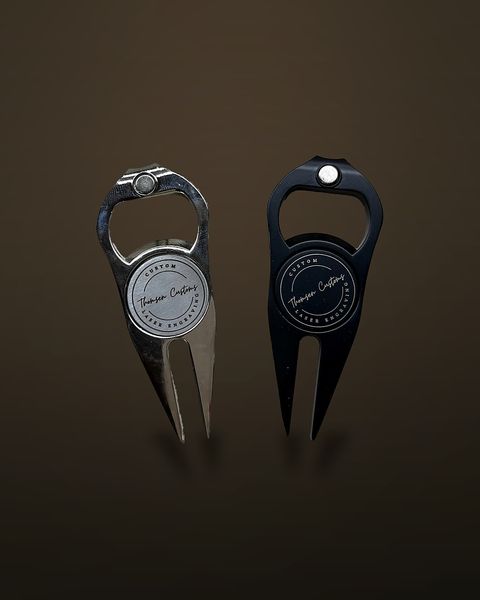 Two golf divot tools with integrated bottle openers, one chrome and one matte black, each with a round magnetic ball marker engraved with the Thomsen Customs logo.